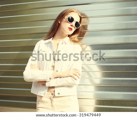 Portrait fashion young woman in sunglasses and white denim jacket over metal textured background