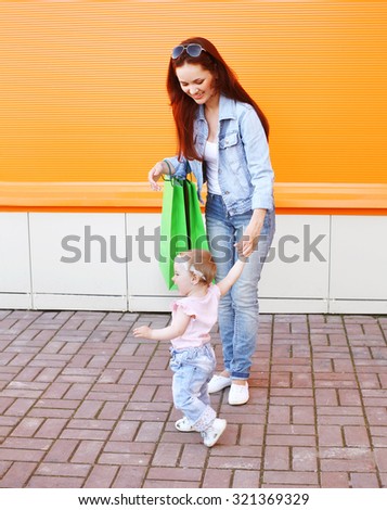 Happy mom and baby with shopping bags walking in city