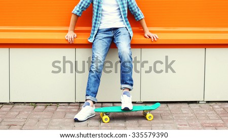 Stylish teenager boy wearing a checkered shirt and jeans on skateboard over colorful background