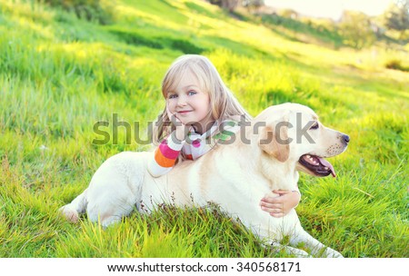 Happy child and labrador retriever dog lying on grass in summer day