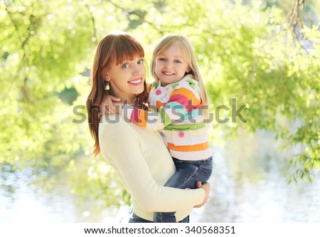 Portrait happy smiling mother and child hugging in summer day