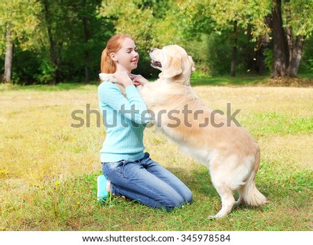 Happy owner woman playing with Golden Retriever dog on grass