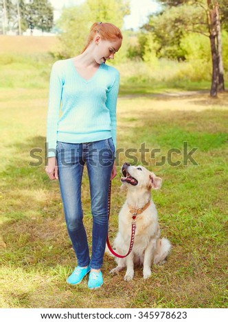 happy owner woman and Golden Retriever dog walking in park