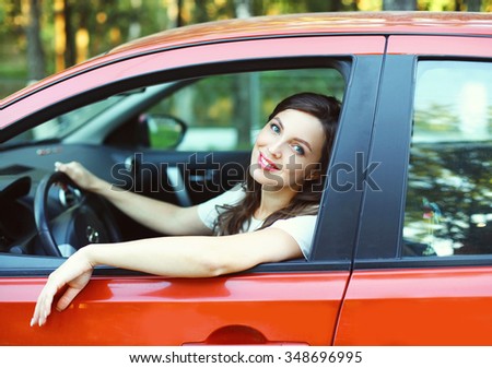 Pretty young woman driver behind the wheel red car