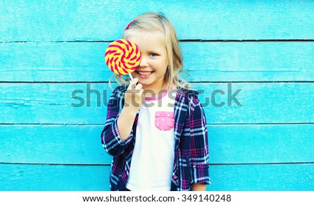Happy smiling child with sweet lollipop having fun over colorful blue background