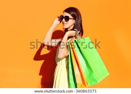 Beautiful brunette woman wearing a dress with shopping bags in city