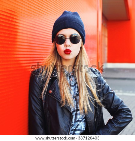 Fashion woman blowing lips with red lipstick wearing a rock black style having fun in city