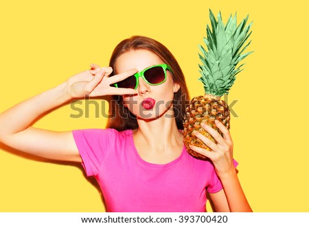 Fashion portrait cool girl in sunglasses and pineapple over yellow background