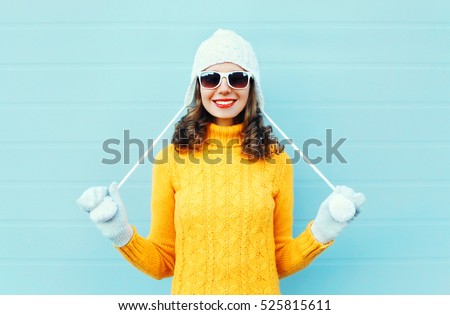 Portrait happy young smiling woman wearing a sunglasses, knitted hat, sweater over blue background