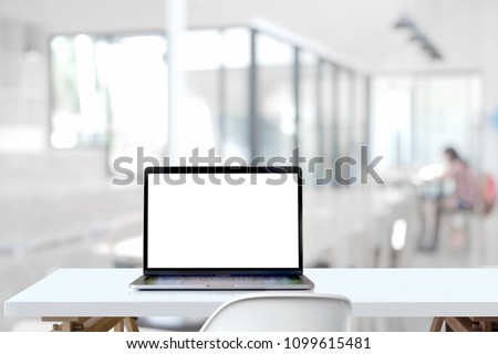 Mockup blank screen laptop on wood table in co-working space.