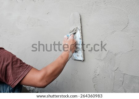 Man working trowel on wet cement wall