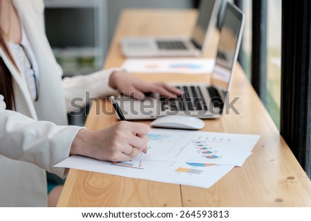 Business Girl analyzing investment charts with laptop.