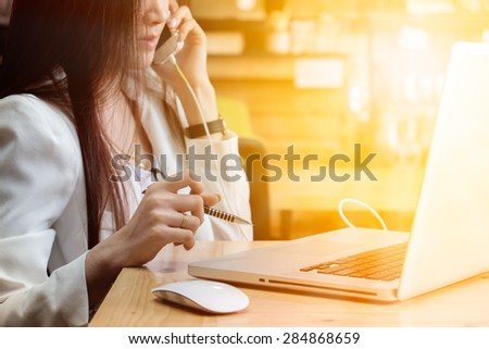 Asian young business woman use laptop sitting at wooden table of modern coffee shop