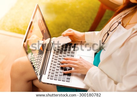 Asian woman holding credit card and typing keyboard laptop for online shopping.