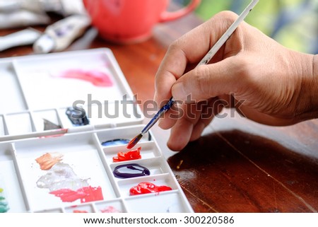 A man painting water colors on paper,Palette of watercolor paints