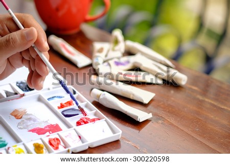 A man painting water colors on paper,Palette of watercolor paints