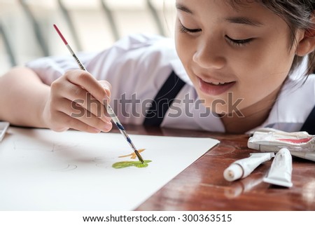 Asian girl painting brush watercolors on paper.