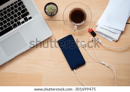 Office table with notepad, smart phone, notebook and cup of coffee. View from above with copy space