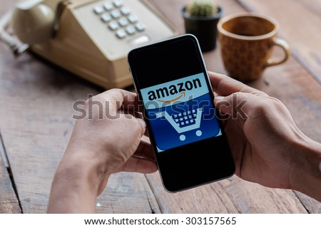 A man holding Amazon logo on screen.Amazon.com, Inc. is an American international electronic commerce company. It is the world\'s largest online retailer.CHIANG MAI,THAILAND - AUG 05,2015