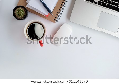 Wood desk with office supplies and red cup of coffee, top view