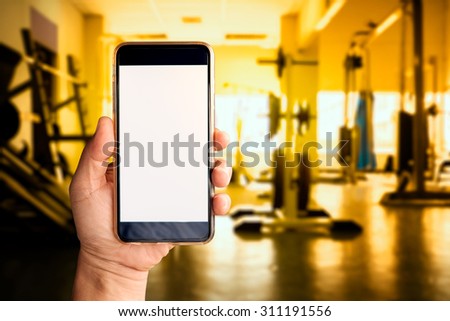 A man hand holding empty screen of smart phone device in Gym.