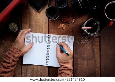 Photographer writing notebook on a wooden desk.Hands writing notebook.