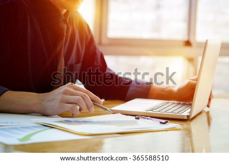 Close up of hand of business man working document and laptop in office morning light.
