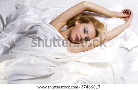 Girl relaxing in bed wrapped in white sheets