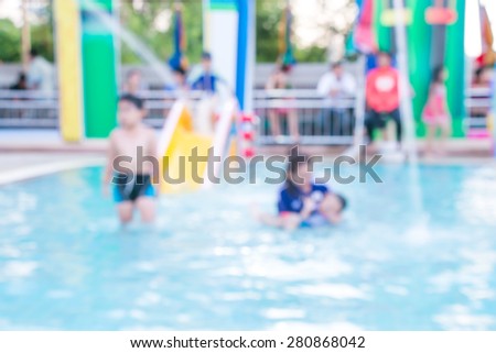 Blurred mom and children has fun playing in water fountains in water park