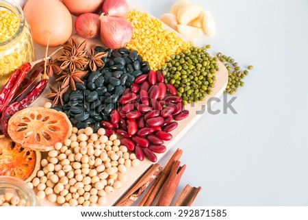 Red beans, mung beans, soybeans, black beans, quince, pepper, anise, onion on a wooden cutting board.
