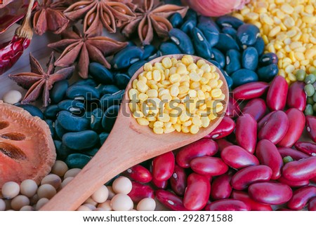 Red beans, mung beans, soybeans, black beans, quince, pepper, anise, onion on a wooden cutting board.