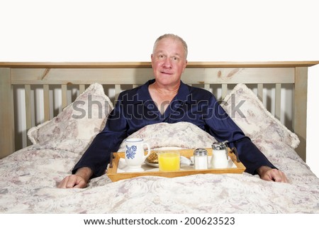 Happy man in his pajamas enjoying breakfast in bed