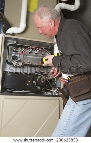 Repairman servicing or repairing basement furnace unit