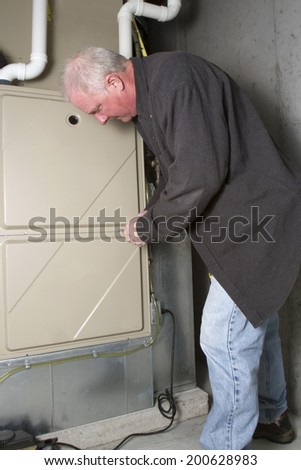 Repairman servicing or repairing basement furnace unit