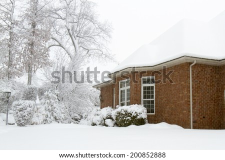 Classic brick home white with fallen snow during a winter storm