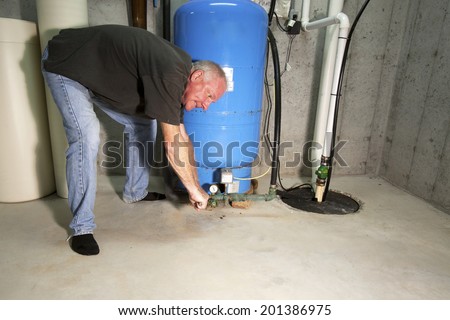 Man with angry, red face bent over well pump with a wrench
