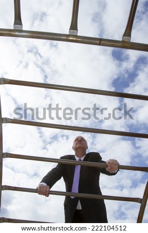 Man in business suit climbing a jungle gym like advancing of the corporate ladder