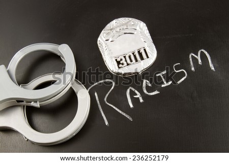 The word RACISM on a chalkboard with a police badge and handcuffs