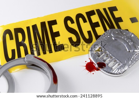 Crime scene tape with blood covered police badge and handcuffs