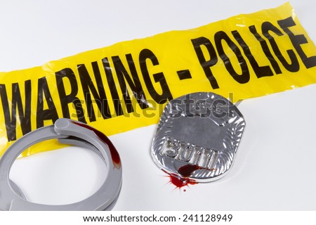 Police warning tape with blood covered police badge and handcuffs