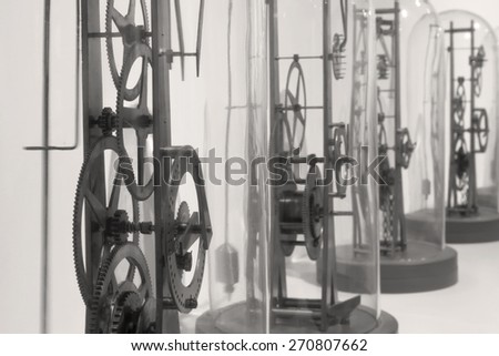 Gears and dials of clock works under glass rendered in black and white