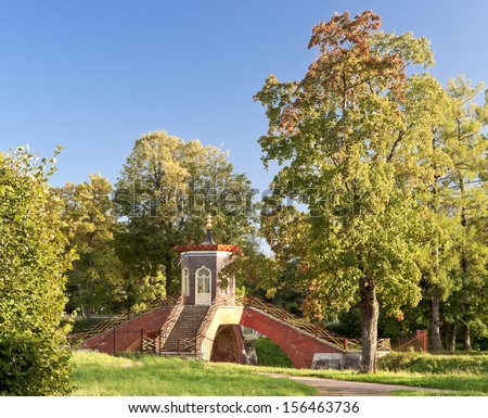 Cross-tip bridge with pagoda style pavilion on it in autumn Aleksandrovsky park