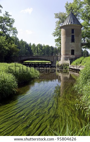 Water mill and the bridge over river with  water-weed in front