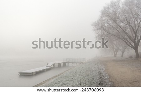 Winter river with pier in morning mist and drizzle