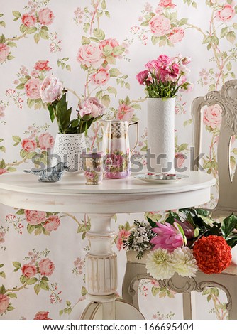 Vases with flowers on a coffee table with floral background