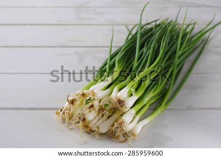 Green spring onions on wood board