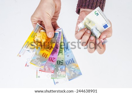 female hand holding banknotes Swiss franc and the second crumpled euro banknotes