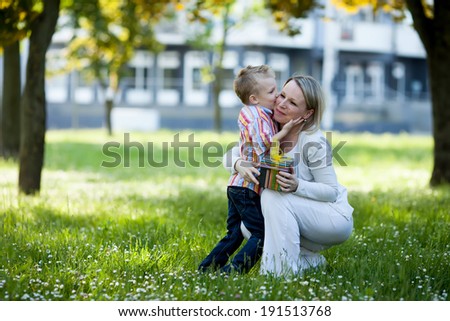 Beautiful boy and mom in spring park with present. Mothers day or birthday celebration concept