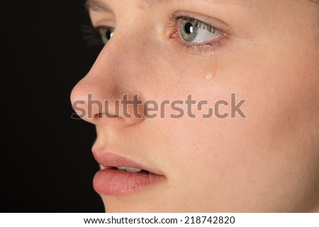 young woman in profile with a tear on her cheek.