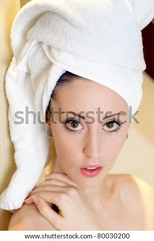 head and shoulders shot of a young woman nude with hair wrapped in a towel looking at the camera